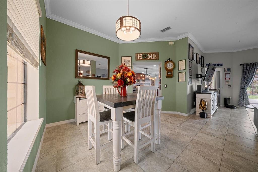 A dining area features a high-top table, green walls, tile flooring, and a pendant light — 6145 SE 96TH STREET, BELLEVIEW, FL