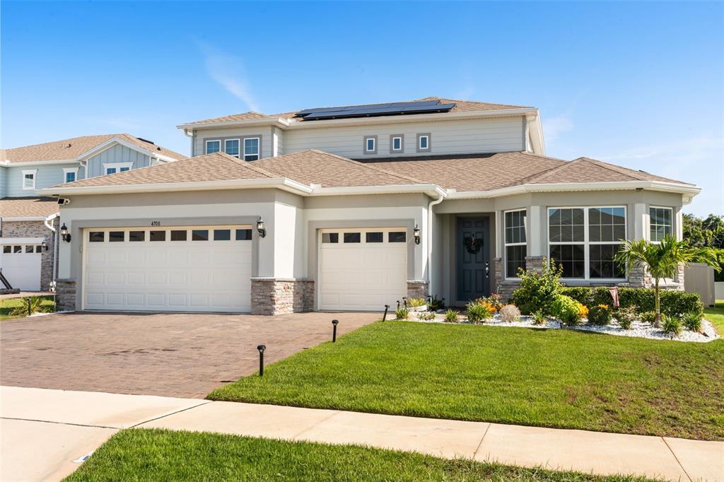 A two-story suburban house features a three-car garage, stone accents, and a paved driveway — 4708 WEATHERBELL ROAD, WINTER GARDEN, FL