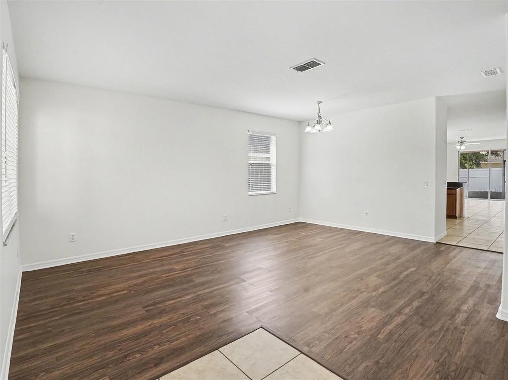 A spacious living room features white walls, wood-look flooring, and a central light fixture — 1942 BEARDSLEY DRIVE, APOPKA, FL