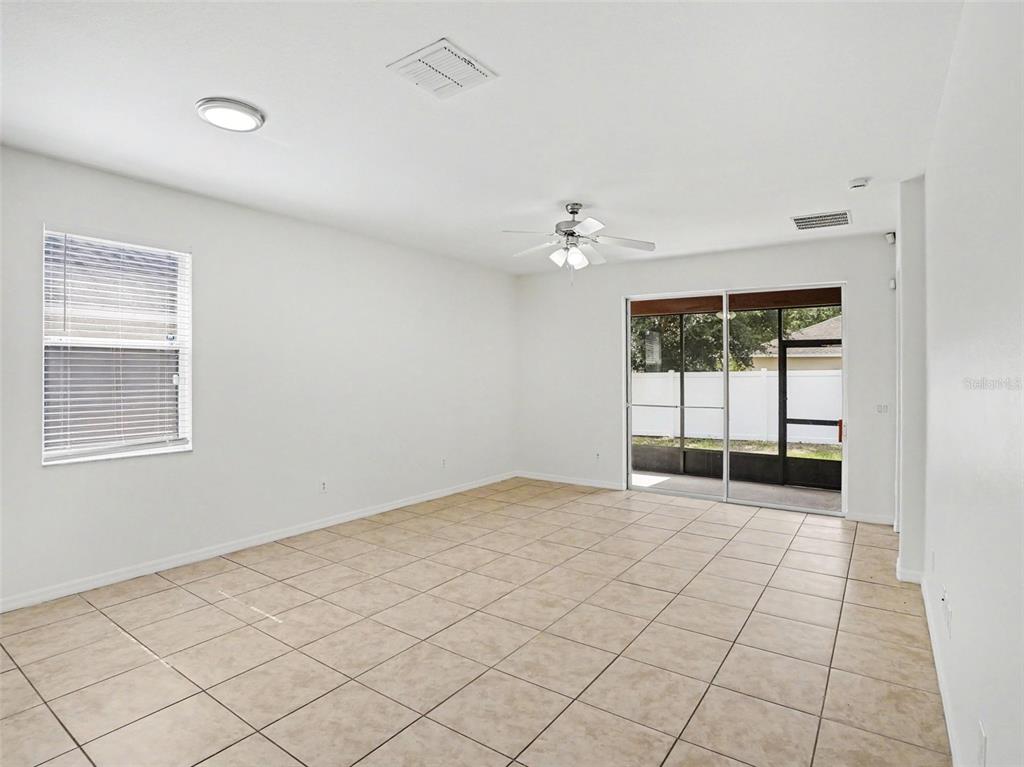 An empty room with beige tile flooring, a ceiling fan, and sliding glass patio doors — 1942 BEARDSLEY DRIVE, APOPKA, FL
