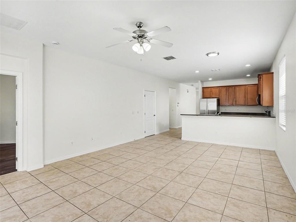 An open-concept living area with tile flooring, a ceiling fan, and an adjacent kitchen — 1942 BEARDSLEY DRIVE, APOPKA, FL