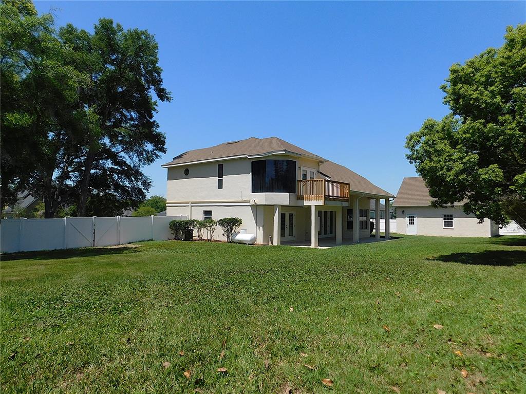 The rear exterior of a two-story house features a wooden deck and a white fence — 1203 SE 49TH AVENUE, OCALA, FL