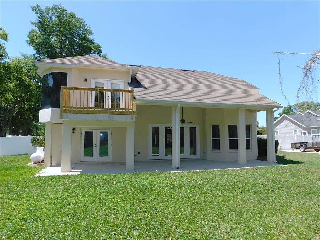 The rear exterior of a two-story house features a covered patio, balcony, and lawn — 1203 SE 49TH AVENUE, OCALA, FL