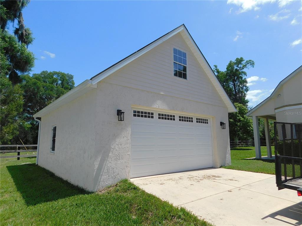A detached garage with a white stucco exterior, a single garage door, and a gable window — 1203 SE 49TH AVENUE, OCALA, FL