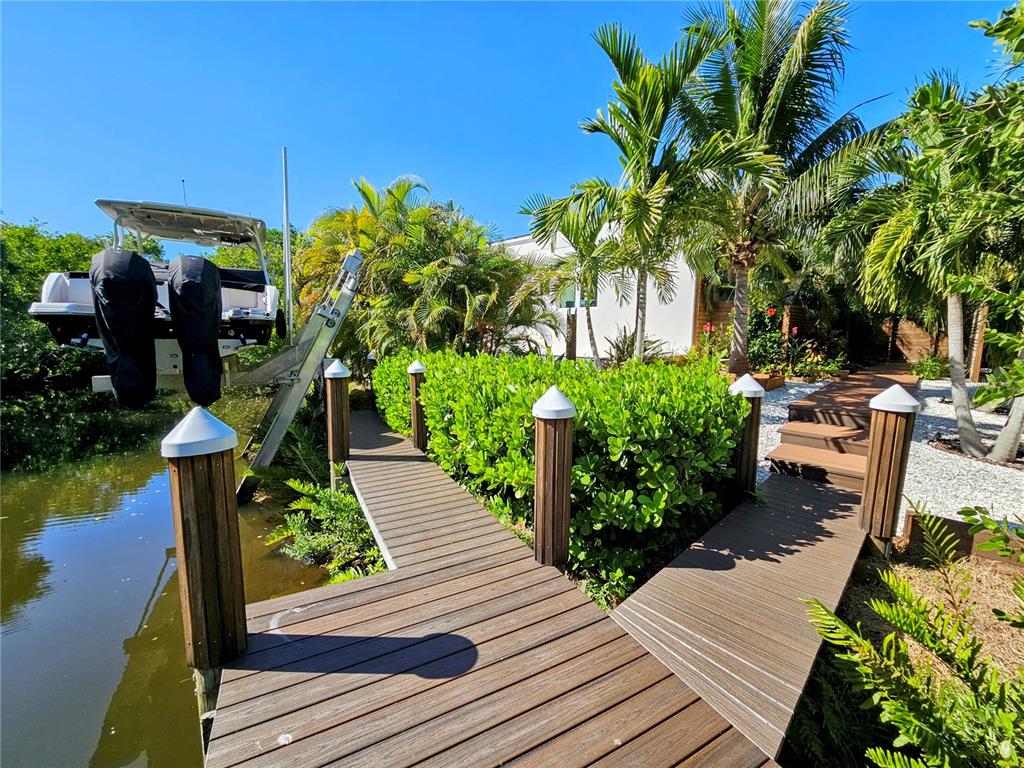 A wooden dock with a boat lift leads to a landscaped yard with palm trees — 2408 NASSAU STREET, SARASOTA, FL