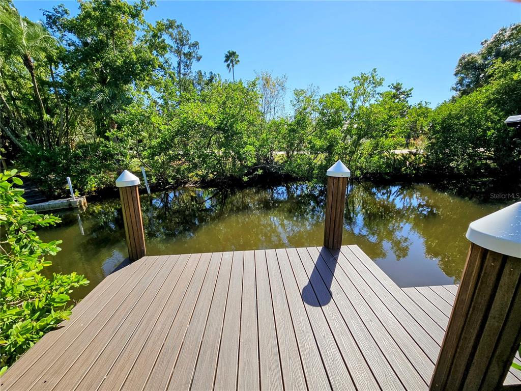 A wooden boat dock overlooks a calm canal surrounded by lush green trees — 2408 NASSAU STREET, SARASOTA, FL