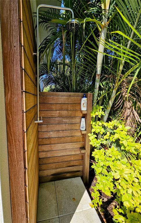 An outdoor shower features a metal rainfall showerhead, wooden slat walls, and built-in shelving — 2408 NASSAU STREET, SARASOTA, FL