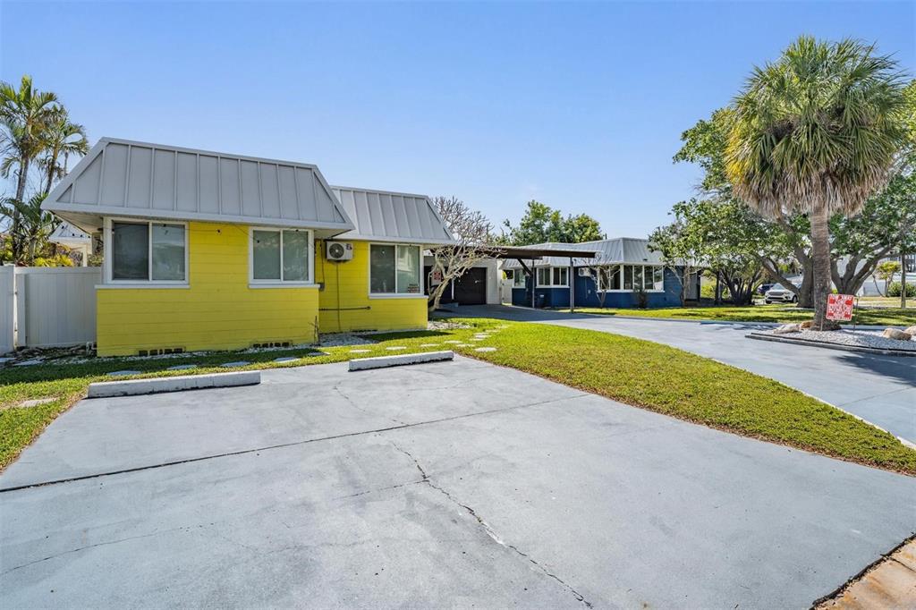 A yellow house with a metal roof and a paved parking area in front — 14060 MIRAMAR AVENUE, ST PETERSBURG, FL