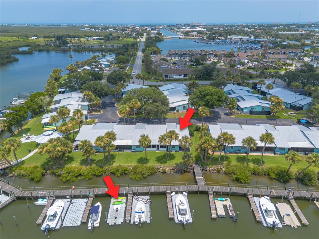 An aerial view shows waterfront townhomes with private boat slips along a dock — 76 HEATHER POINT COURT, NEW SMYRNA BEACH, FL