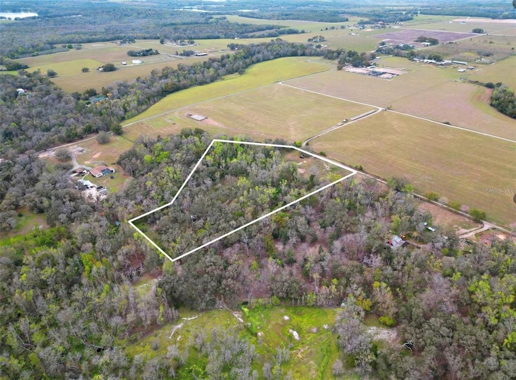An aerial view shows a wooded plot of land outlined in white within a rural landscape — 33234 CHIPCO RANCH ROAD, DADE CITY, FL