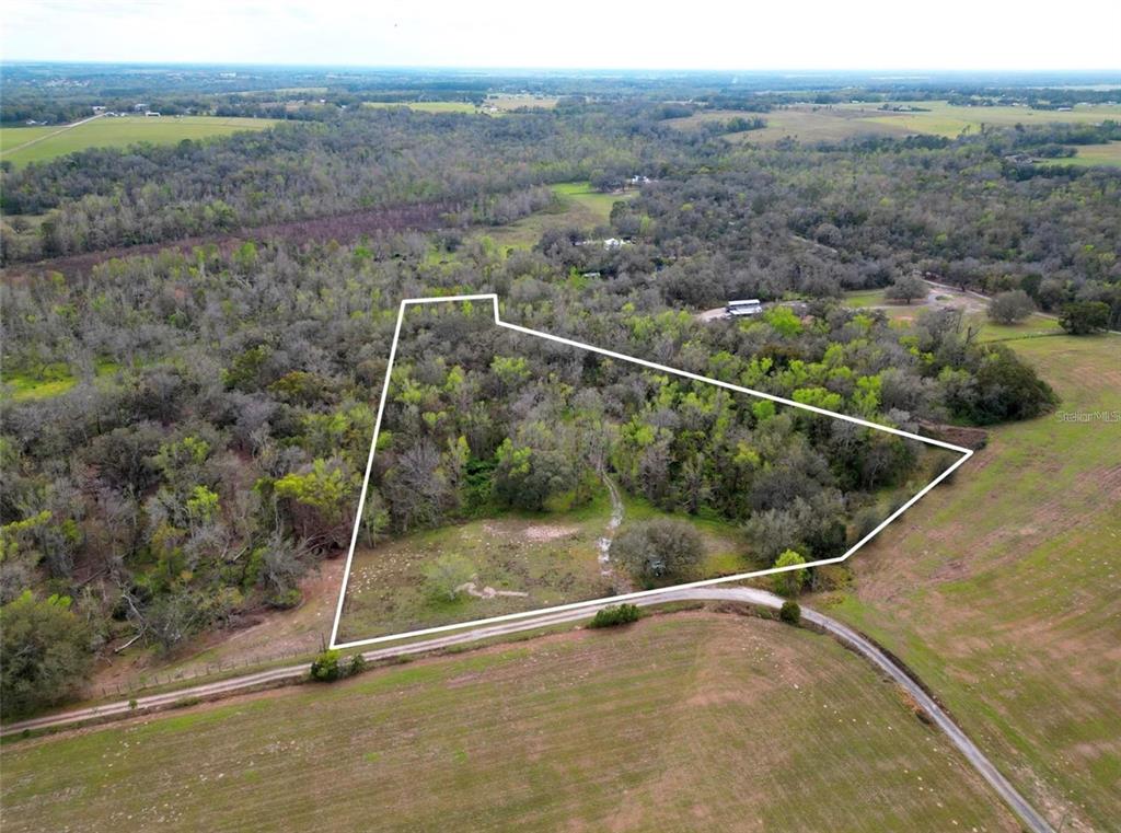 An aerial view shows a wooded plot of land outlined in white near a road — 33234 CHIPCO RANCH ROAD, DADE CITY, FL