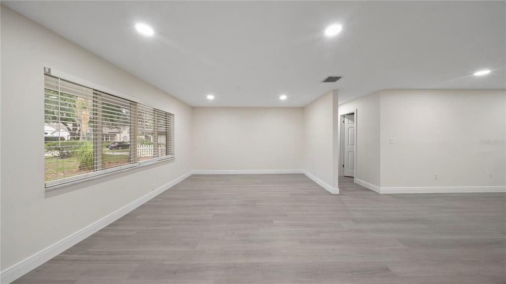 An empty room with light gray wood-look flooring, recessed lighting, and a large window — 2662 DERBYSHIRE ROAD, MAITLAND, FL