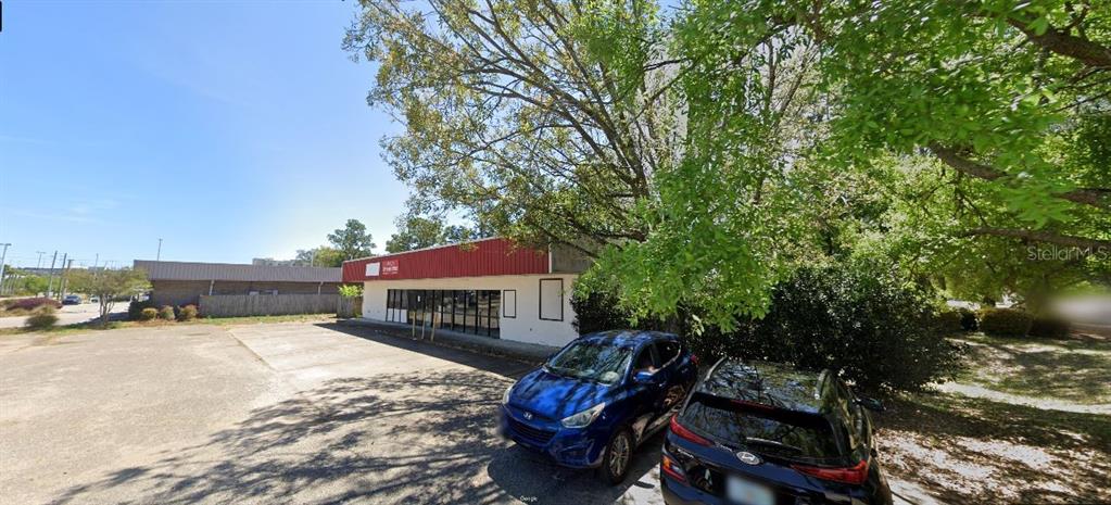 A single-story commercial building with a red roof and a paved parking lot — 1167 COLLEGE BOULEVARD, PENSACOLA, FL