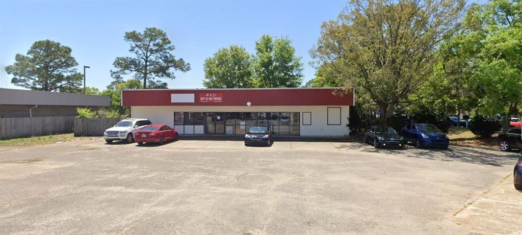 A single-story commercial building with a red roof and a large paved parking lot — 1167 COLLEGE BOULEVARD, PENSACOLA, FL
