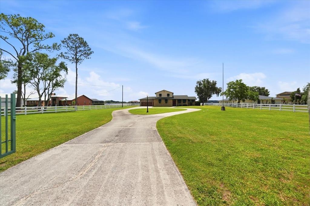 A long concrete driveway leads to a two-story house surrounded by a large grassy lawn — 2731 STATE ROAD 557, LAKE ALFRED, FL