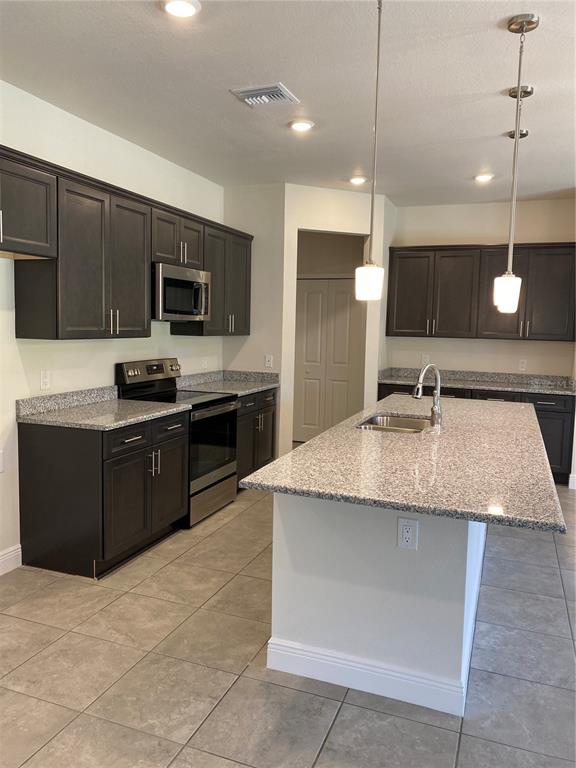 A kitchen features dark wood cabinets, granite countertops, a center island, and stainless steel appliances — 2789 WENONA DRIVE, NORTH PORT, FL