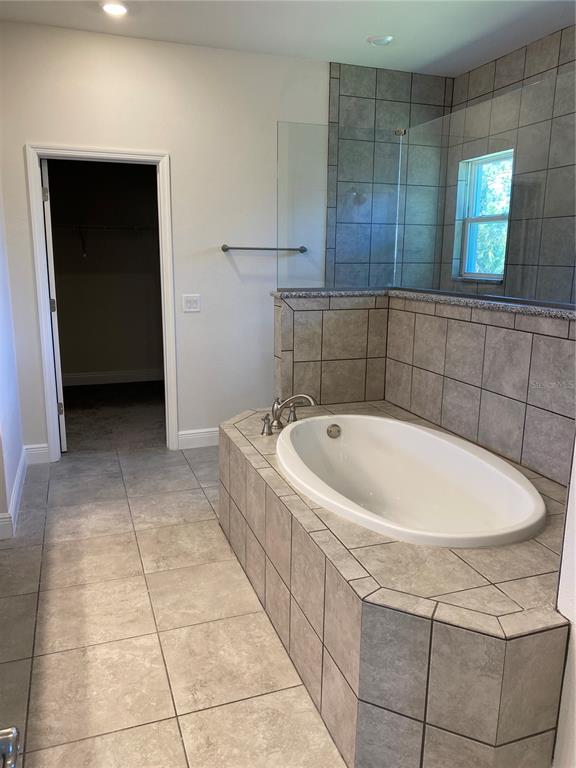 A bathroom features a tiled soaking tub, a glass shower enclosure, and a doorway to a closet — 2789 WENONA DRIVE, NORTH PORT, FL