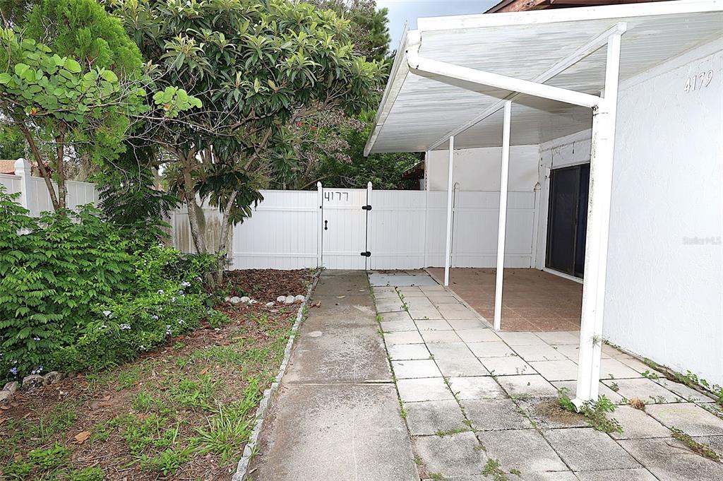 A concrete patio with a white metal awning sits beside a white vinyl privacy fence — 4179 SPITFIRE AVENUE, KISSIMMEE, FL