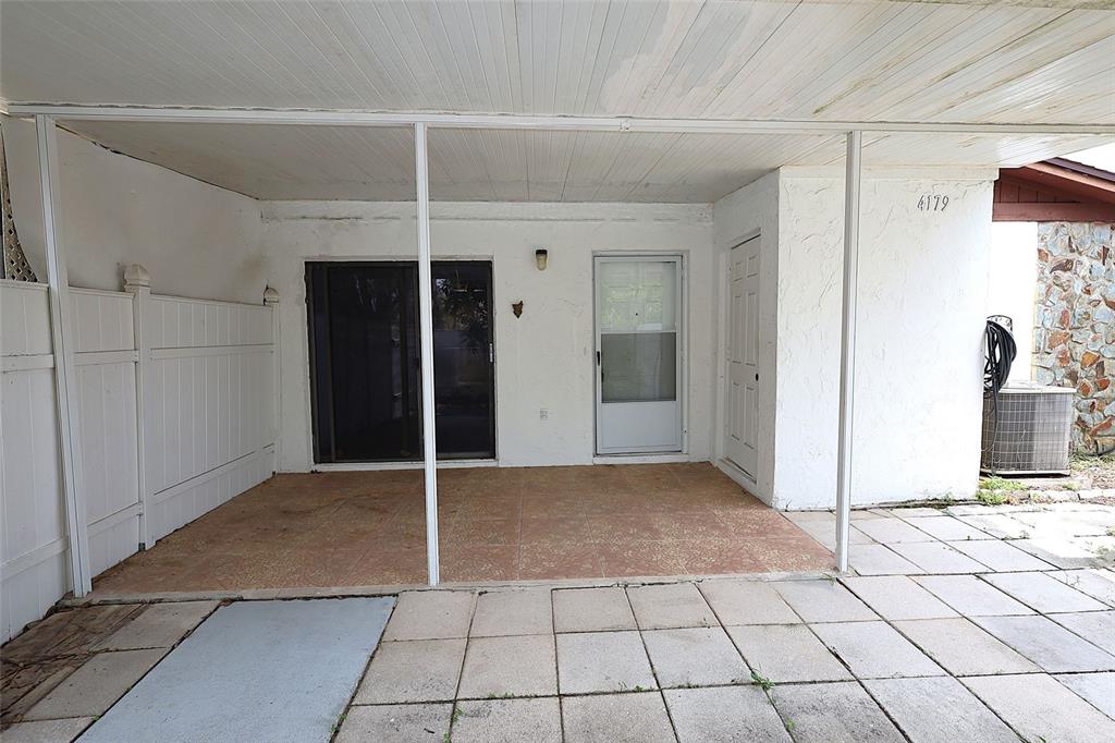 A covered patio features tiled flooring, a sliding glass door, and a white entry door — 4179 SPITFIRE AVENUE, KISSIMMEE, FL