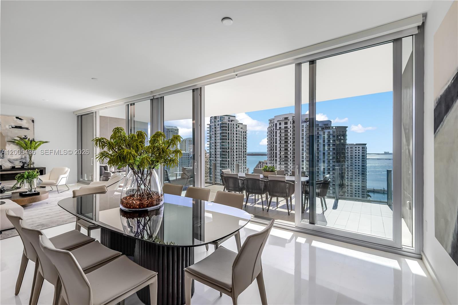 A dining room with a glass table and floor-to-ceiling windows overlooking a city skyline — 300 Biscayne Blvd Way # 2802, Miami FL 33131, MIAMI, FL