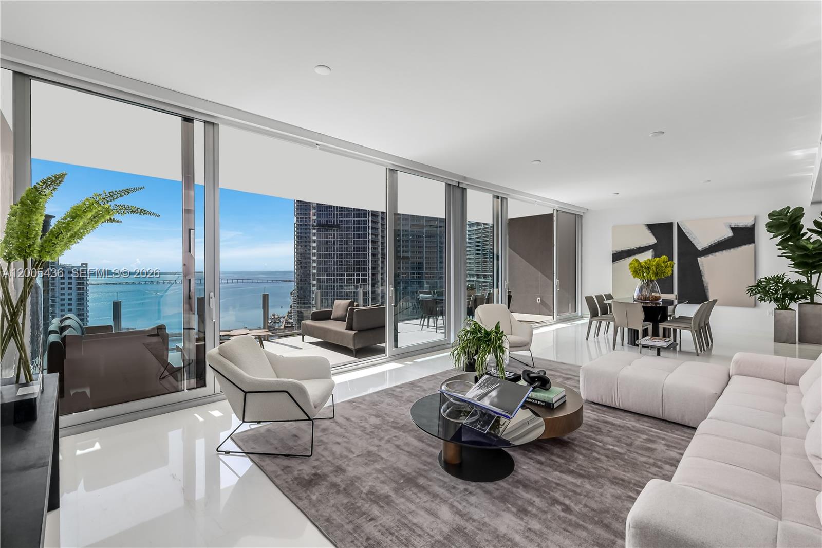 A modern living and dining area features floor-to-ceiling windows with a balcony and water view — 300 Biscayne Blvd Way # 2802, Miami FL 33131, MIAMI, FL