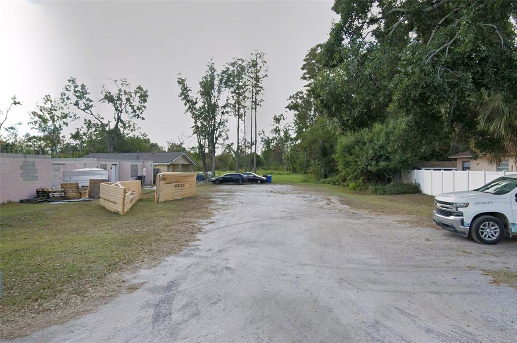 A gravel driveway leads toward a house under construction with stacked lumber in the yard — 6810 N BLOSSOM AVENUE, TAMPA, FL
