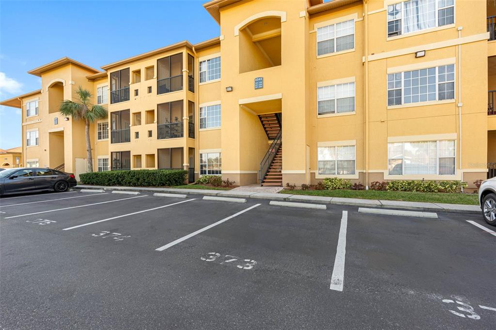 A three-story yellow apartment building with a parking lot in the foreground — 4343 BAYSIDE VILLAGE DRIVE UNIT 104, TAMPA, FL