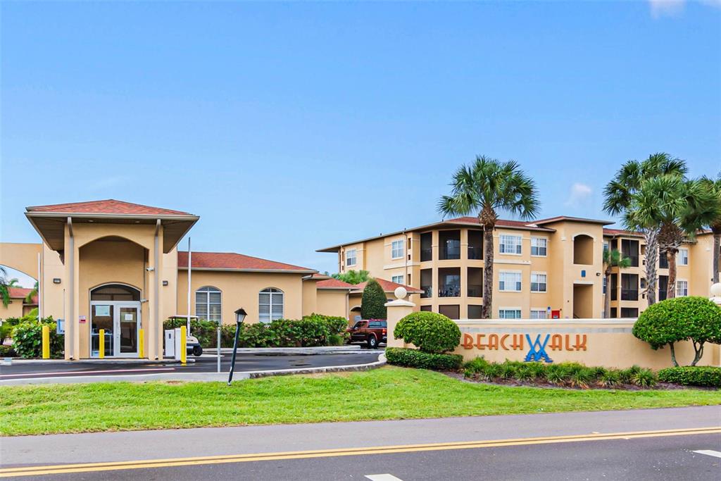 The exterior of a multi-story apartment complex features a gated entrance and a sign reading Beachwalk — 4343 BAYSIDE VILLAGE DRIVE UNIT 104, TAMPA, FL