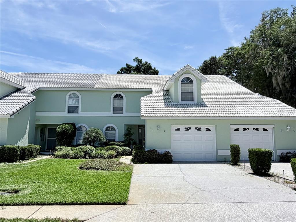 A two-story light green house with a white tiled roof and a two-car garage — 706 MORAY DRIVE, INVERNESS, FL