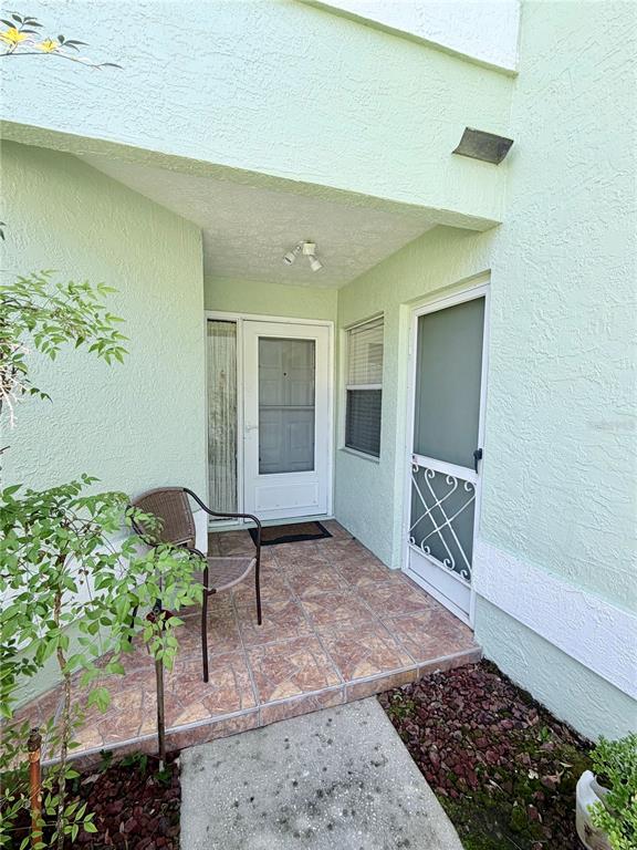 An exterior view of a tiled entryway with two doors and a small patio chair — 706 MORAY DRIVE, INVERNESS, FL