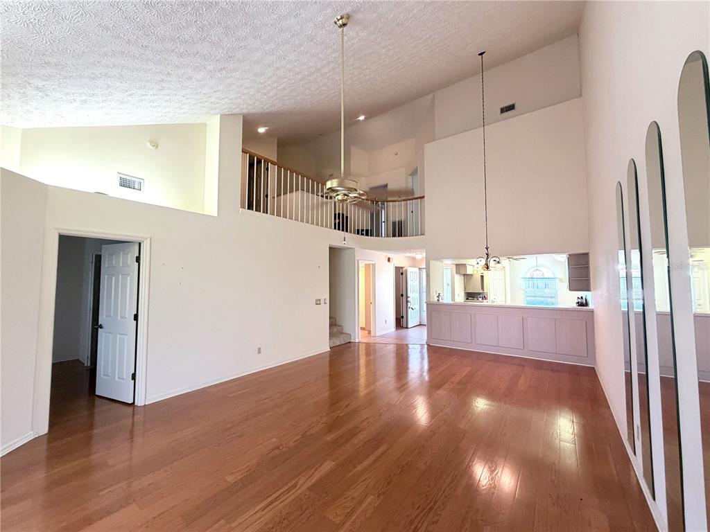 A spacious living room features high vaulted ceilings, hardwood floors, and a lofted balcony area — 706 MORAY DRIVE, INVERNESS, FL