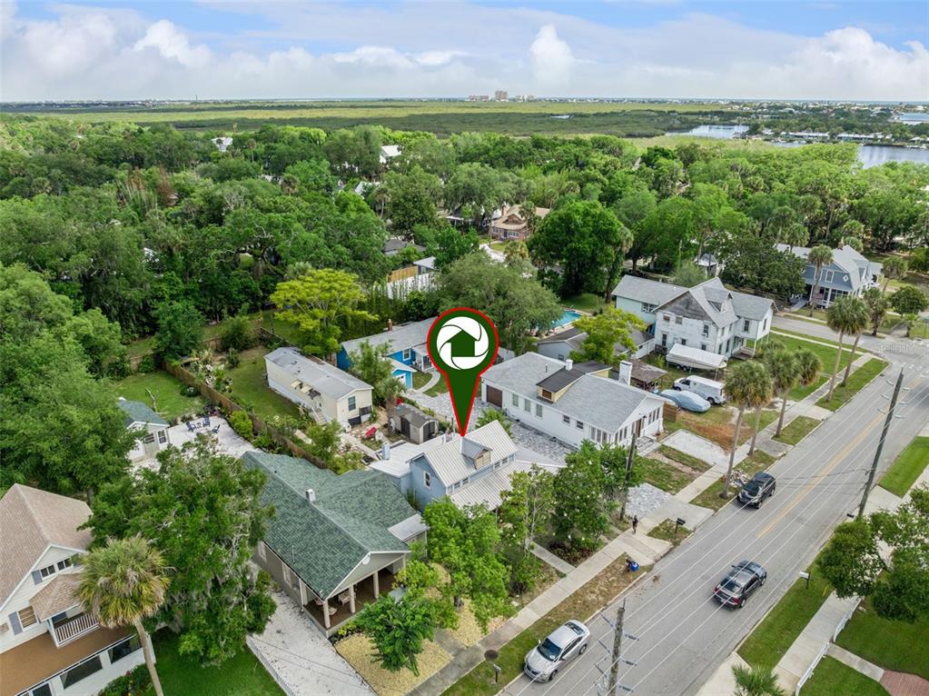An aerial view shows a blue house with a metal roof along a residential street — 207 MARY AVENUE, NEW SMYRNA BEACH, FL