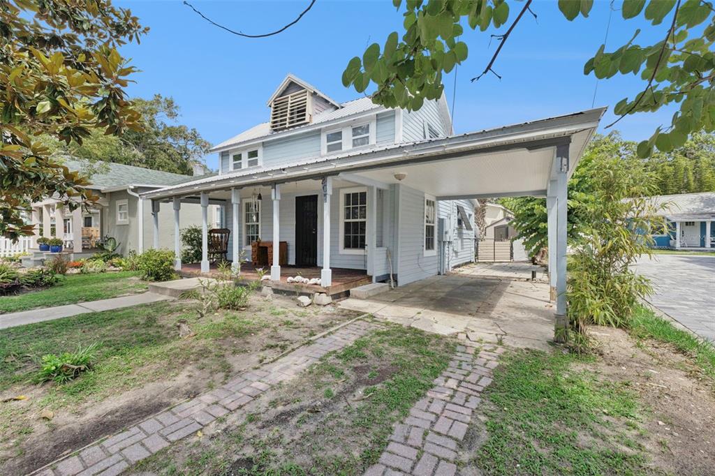 A light blue two-story house features a front porch, a carport, and a brick walkway — 207 MARY AVENUE, NEW SMYRNA BEACH, FL