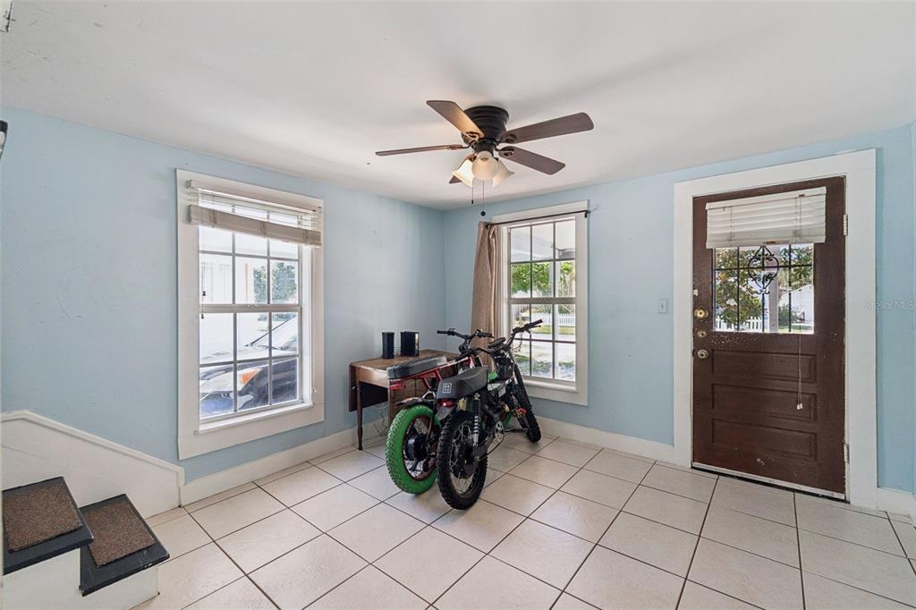 A room with light blue walls, white tile flooring, a ceiling fan, and two parked motorcycles — 207 MARY AVENUE, NEW SMYRNA BEACH, FL