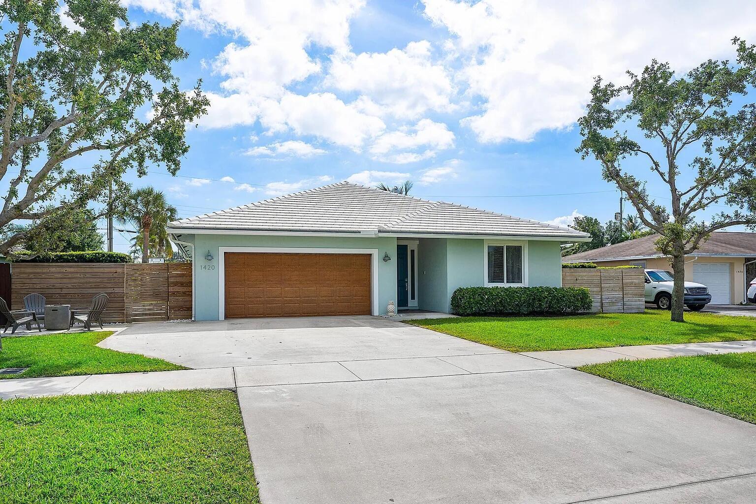 A light green single-story house features a brown garage door and a concrete driveway — 1420 High Ridge Road, FL 33461, FL