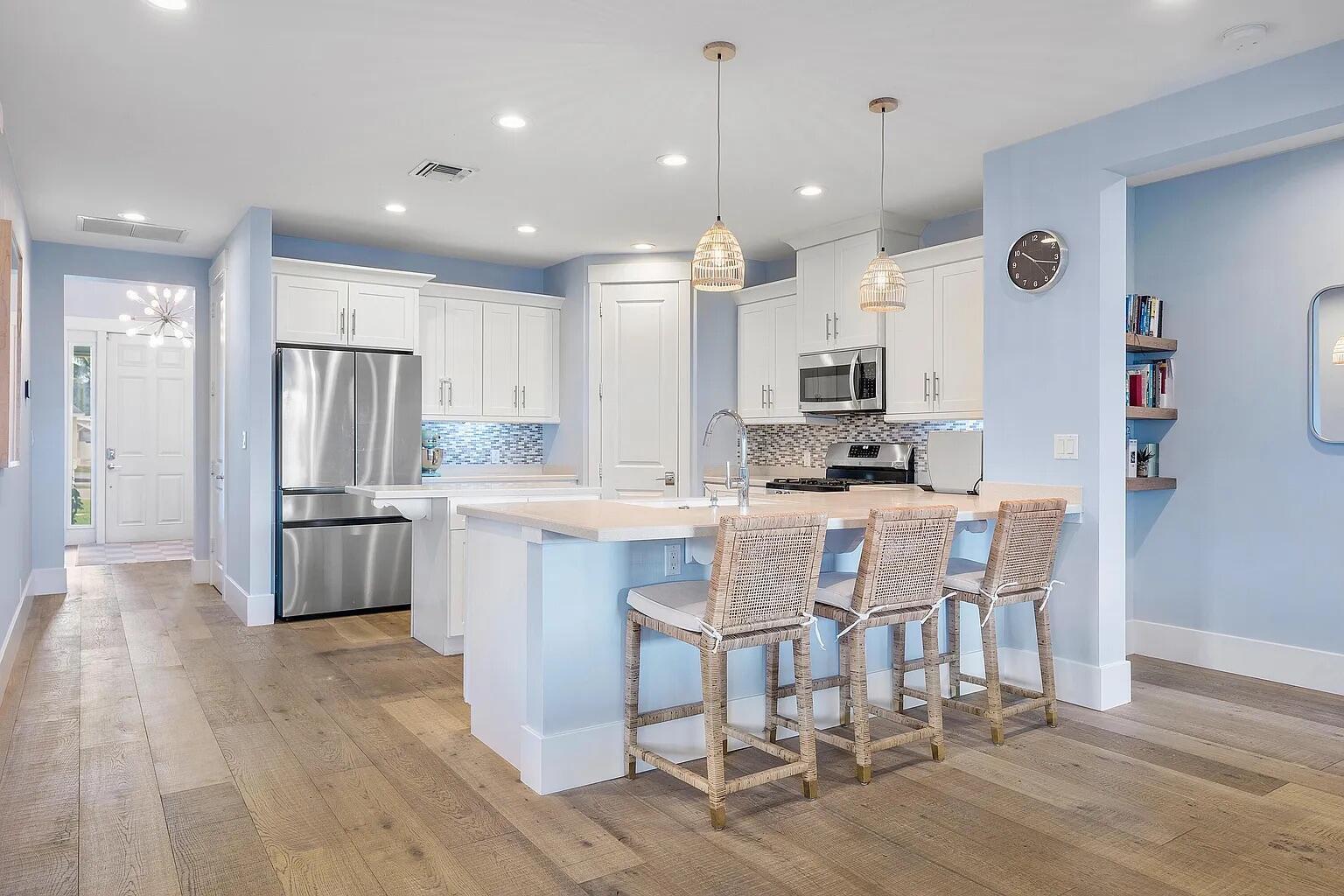 A kitchen features white cabinets, stainless steel appliances, a breakfast bar, and light blue walls — 1420 High Ridge Road, FL 33461, FL