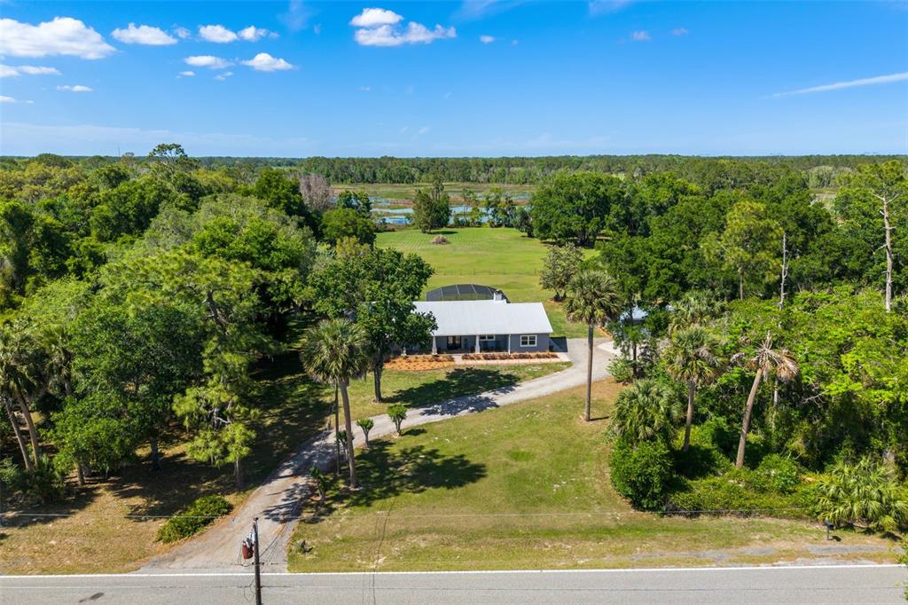 An aerial view shows a house with a screened pool surrounded by trees and grass — 650 OLD MIMS ROAD, GENEVA, FL