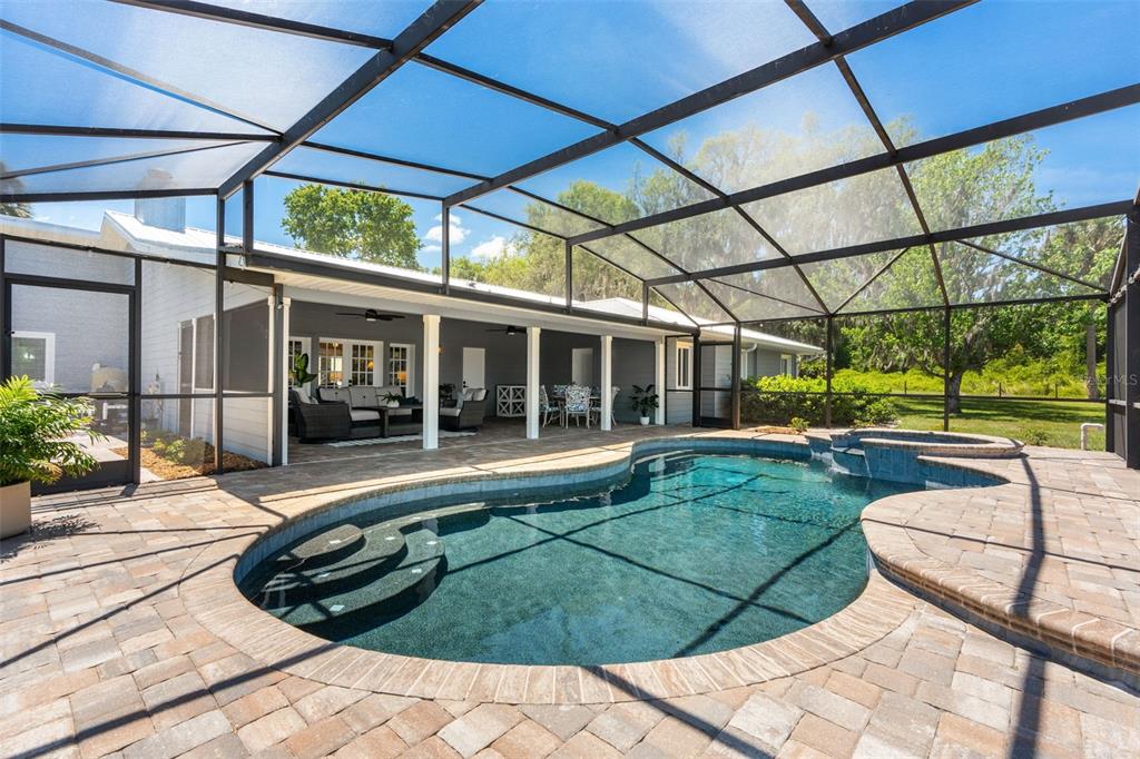 A screened-in patio features a swimming pool with a spa and paver decking — 650 OLD MIMS ROAD, GENEVA, FL