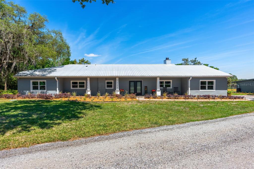 A single-story gray house with a metal roof sits behind a gravel driveway and lawn — 650 OLD MIMS ROAD, GENEVA, FL