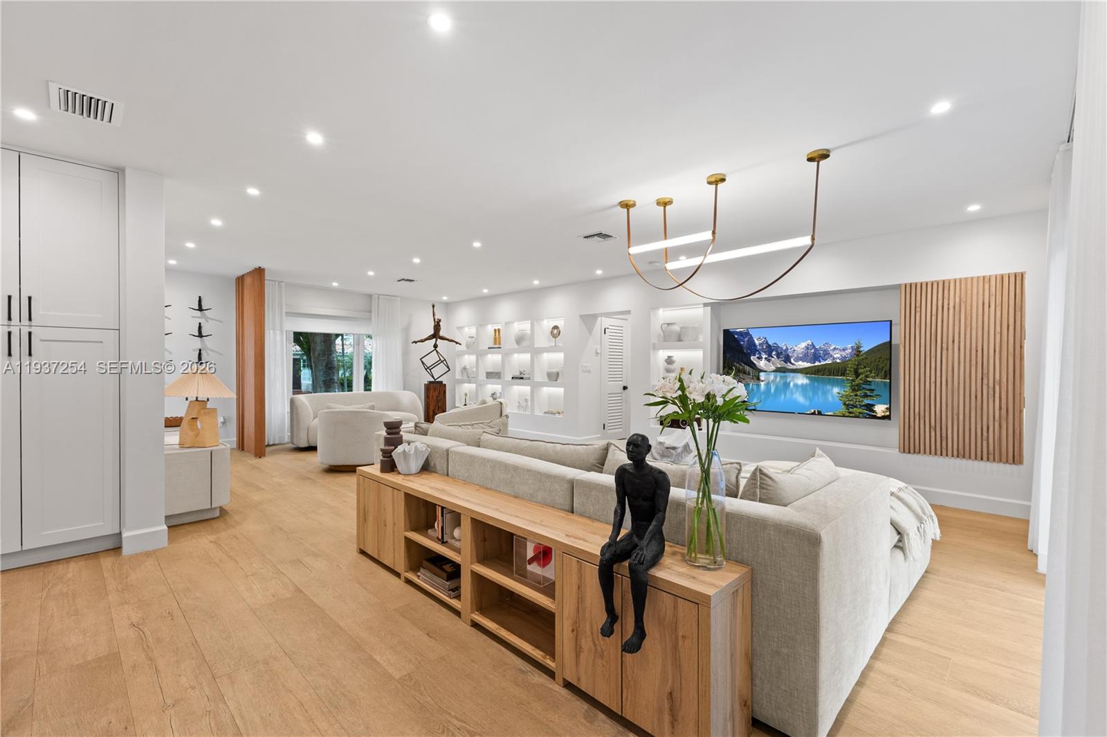 A modern living room features a large sectional sofa, wooden console table, and wall-mounted television — 800 NE 72nd St, Miami FL 33138, MIAMI, FL