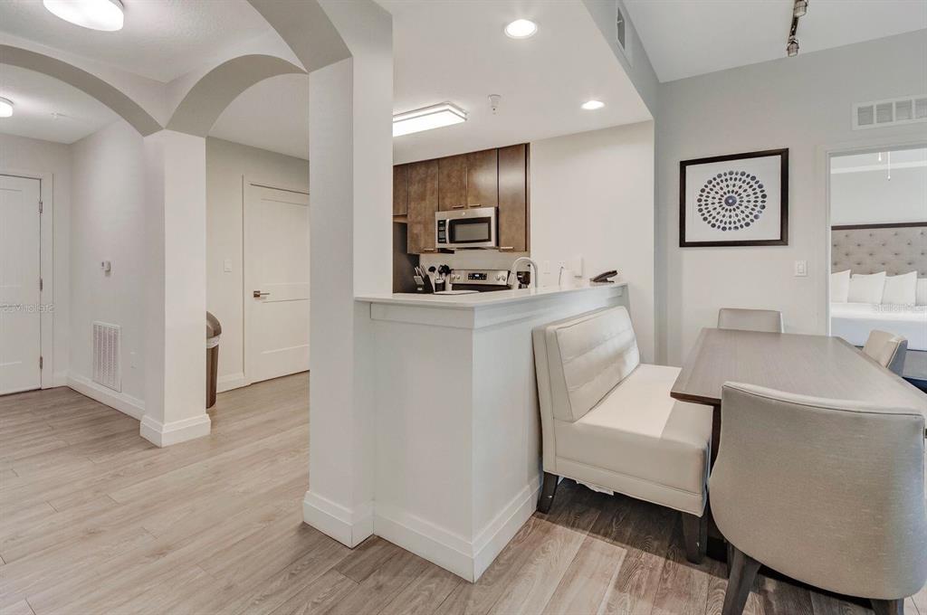 A kitchen with dark cabinets and a breakfast bar overlooks a dining area with seating — 14501 GROVE RESORT AVENUE UNIT 3706, WINTER GARDEN, FL