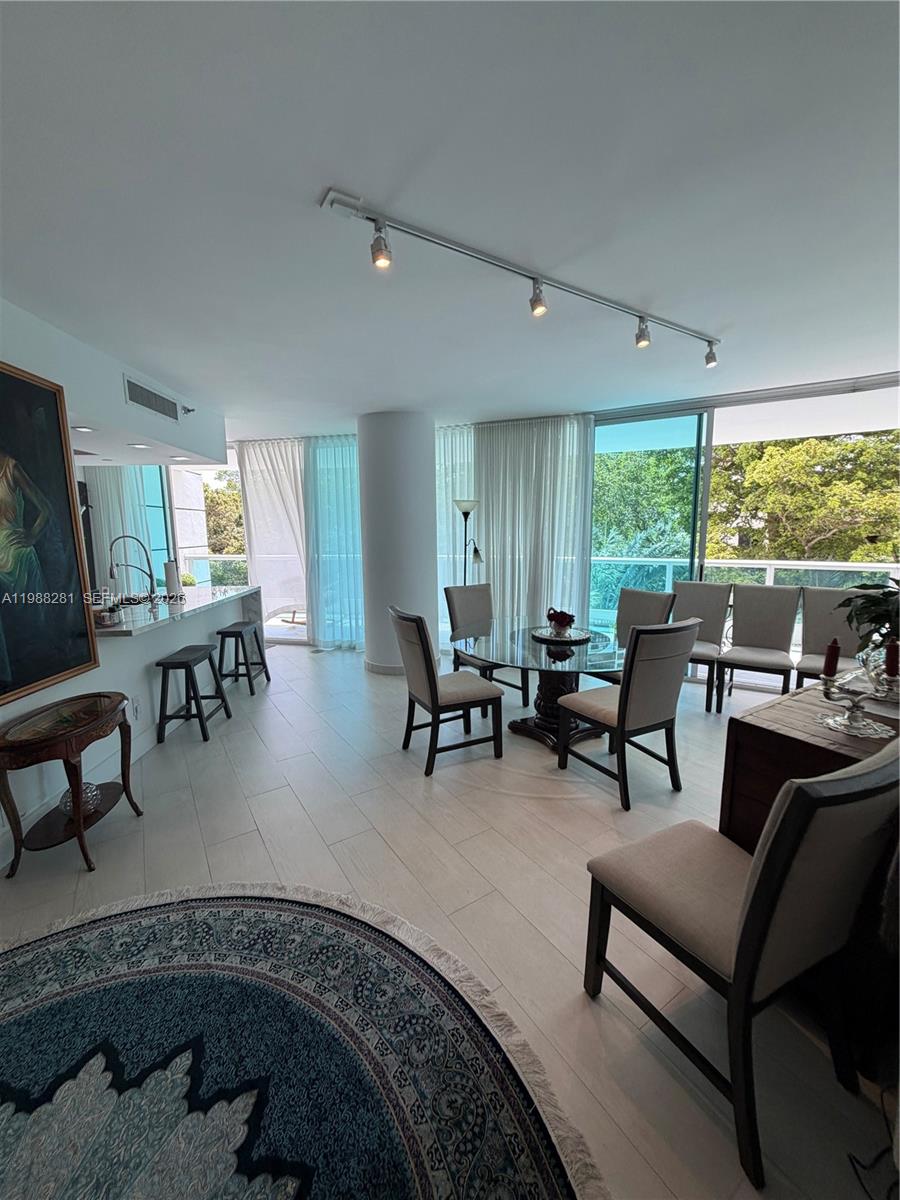A dining and kitchen area features light wood floors, a glass table, and floor-to-ceiling windows — 2127 Brickell Ave # 502, Miami FL 33129, MIAMI, FL