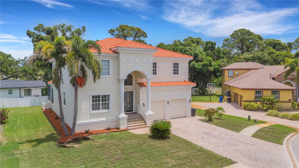 A two-story house with a red tile roof, beige stucco walls, and a paved driveway — 3021 59TH AVENUE S, ST PETERSBURG, FL