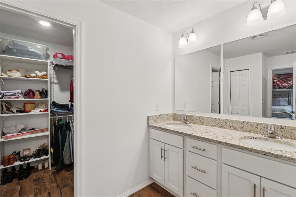 A bathroom with a double-sink granite vanity, white cabinets, and an adjacent walk-in closet — 1830 RADCLIFF AVENUE SE, PALM BAY, FL