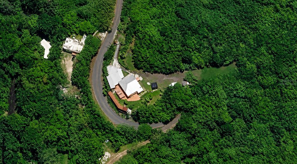 An aerial view shows a house with a white roof situated along a curved road — 123 CARR, PONCE, PR