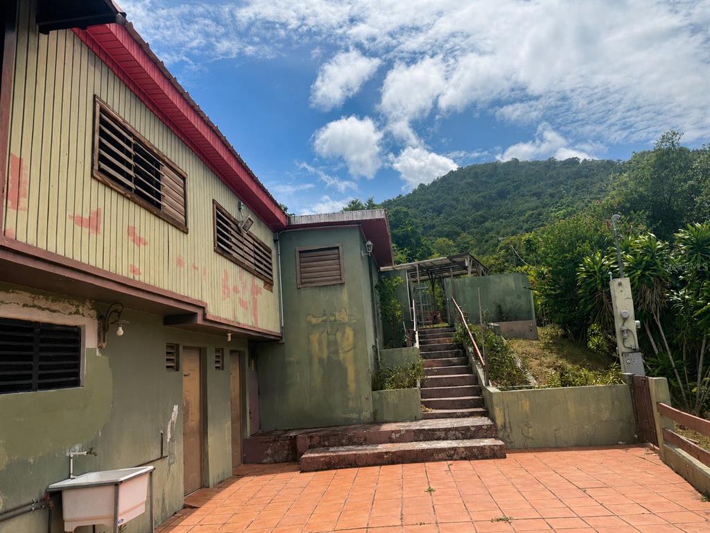An exterior view of a house with a tiled patio, stairs, and a mountain backdrop — 123 CARR, PONCE, PR