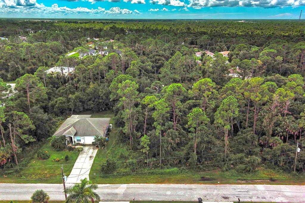 An aerial view shows a single-story house with a driveway surrounded by dense forest — SHAFFER AVENUE, NORTH PORT, FL