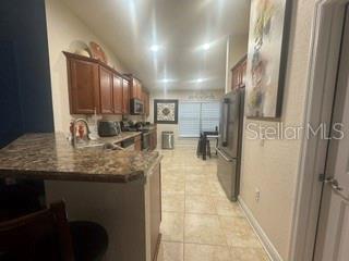 A kitchen features wood cabinets, granite countertops, stainless steel appliances, and light-colored tile flooring — 12244 LEGACY BRIGHT STREET, RIVERVIEW, FL