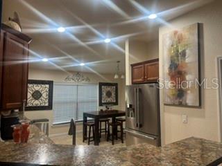 A kitchen with dark wood cabinets, granite countertops, and a dining area with bar stools — 12244 LEGACY BRIGHT STREET, RIVERVIEW, FL