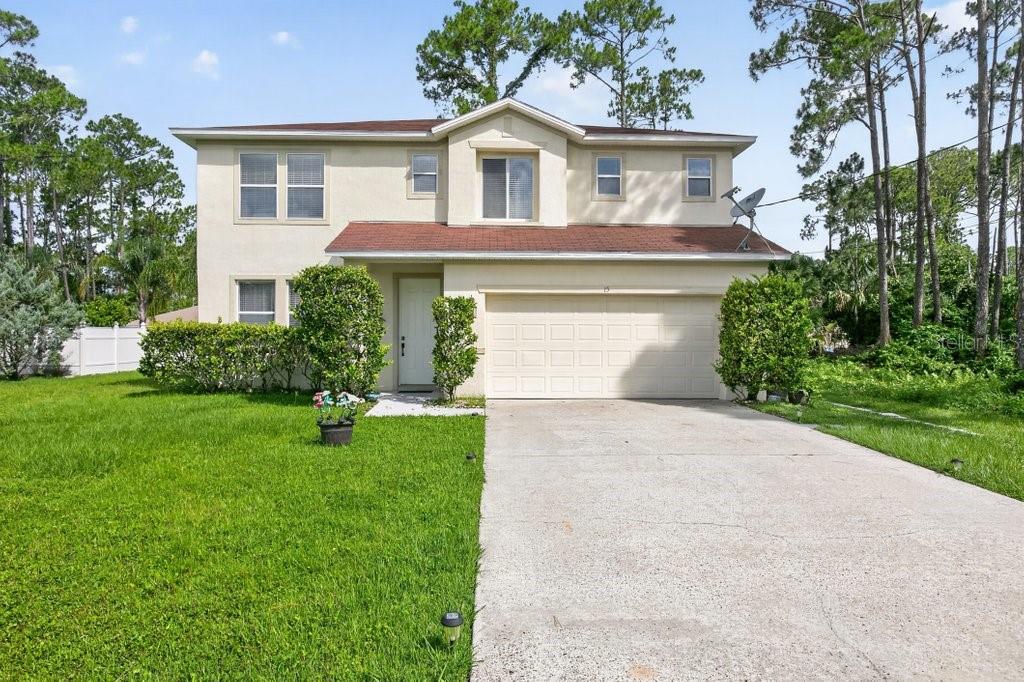 A two-story house with a beige stucco exterior, a red roof, and a concrete driveway — 15 RYKER LANE, PALM COAST, FL
